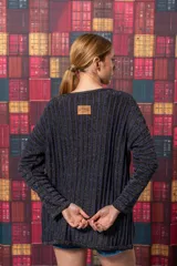 Buzo negro de tejido de punto con rayas verticales plateadas, corte holgado y mangas largas.