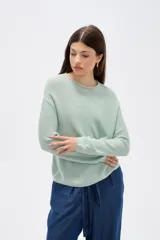 Sweater de tejido de punto fino en color blanco, con cuello redondo a la base y mangas largas de corte holgado.