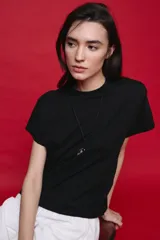 Remera negra de manga corta con cuello redondo y silueta amplia, de hombros caídos y textura suave.