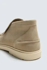 Bota casual de piel con acabado serraje color beige, con detalle de bordón en el empeine, horma redonda y suela a contraste.