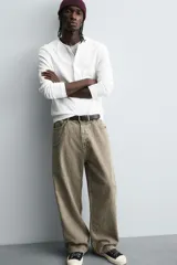 Pantalón de corte baggy fit confeccionado en tejido de algodón con textura y efecto lavado. Presenta diseño de cinco bolsillos, cierre frontal con cremallera y botón.