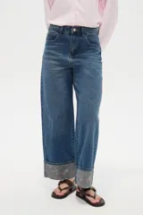 Pantalón jean de corte baggy y tiro medio, con diseño amplio y dobladillo vuelto que deja ver un detalle estampado en el interior.