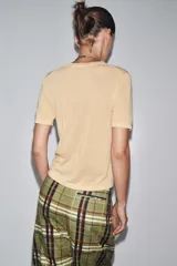 Top de manga corta color beige claro, con cuello redondo y textura de tejido de punto fino.