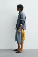 Camisa de manga larga con cuello solapa, bolsillo de plastrón en el pecho y cierre frontal con botones a presión. Presenta un patrón de cuadros vichy en tonos de azul desgastado.