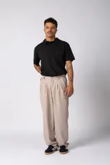 Pantalón sastrero de corte baggy, color beige, con pinzas frontales, cierre de botón y cremallera, y bolsillos laterales.