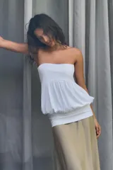Vestido midi de diseño strapless con escote recto. Presenta un cuerpo superior blanco con textura fruncida y una falda inferior en tono beige con caída fluida.