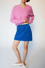 Falda mini de pana azul, con diseño de cinco bolsillos, cierre frontal con cremallera y botón.
