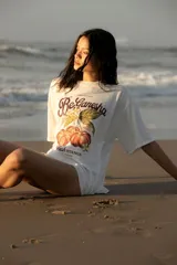 Remera blanca oversize de algodón con estampado de frutas y texto en el frente, pespuntes a contratono y tajos laterales.