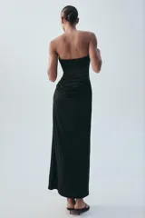 Vestido midi negro de escote palabra de honor, con diseño combinado de paneles de distintos acabados y detalle drapeado en la zona frontal y de la cintura. Cuenta con cierre lateral de cremallera oculta.