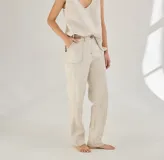 Pantalón largo color crudo, de lino, con bolsillos delanteros y traseros, cierre con botón y presillas para cinturón.