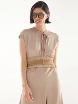 Mono largo color beige con cuello redondo, mangas cortas y cinturón trenzado a la cintura. Presenta aberturas laterales en las piernas y cierre con lazo en el cuello.