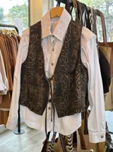 Chaleco de jean con estampado animal print de serpiente en tonos marrones y negros, escote en V y cierre frontal con tiras para atar.