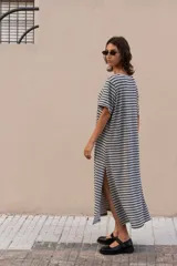 Vestido largo a rayas horizontales grises y negras, con cuello bote, mangas cortas y aberturas laterales. Incluye lazo en la cintura.