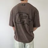 Remera oversize color marrón con efecto acid wash, mangas cortas y gran aplicación bordada en la espalda.