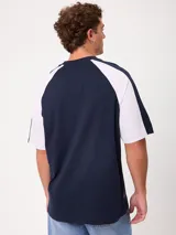 Remera holgada Rusty modelo Isel, de diseño bicolor con cuerpo azul marino y mangas ranglán blancas. Cuenta con cuello redondo ribeteado y pequeño logo bordado en el pecho.
