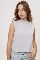 Remera sin mangas negra con cuello redondo y hombros estructurados con hombreras, de corte recto y largo a la cintura.