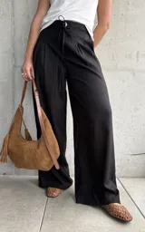 Pantalón negro de lino con pinzas en la cintura, cordón ajustable y corte wide leg.