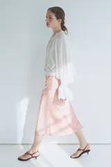 Pollera midi de tiro alto, confeccionada en tela satinada de color rosado con caída suave y leve vuelo en el bajo.