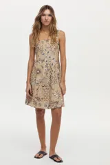 Vestido corto camel de lino y viscosa, con escote cuadrado, breteles anchos y diseño con godets. Presenta un estampado artesanal en tonos marrones y blancos.