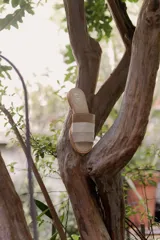 Sandalias tipo chinela de cuero, con diseño de banda ancha que combina cuero liso, cuero texturizado y gamuza en tonos marrones. Presenta plantilla con logo grabado.