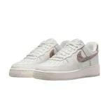 Championes Nike Air Force 1 de corte bajo, color blanco con detalles en textura de piel de serpiente en tono bronce en el swoosh lateral y en el talón.