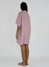 Camisola de lino color gris, con cuello polo, cierre frontal de botones y bolsillo frontal con detalle bordado. Presenta mangas cortas amplias y un corte holgado.