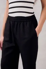 Pantalón negro de lino y viscosa, de tiro medio y corte recto, con cintura elástica.