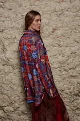 Camisa holgada con estampado geométrico en tonos azules, rojos y marrones. Tiene cuello solapa, mangas largas y cierre abotonado.