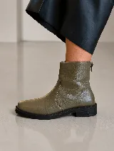 Bota corta de cuero negro con punta cuadrada, taco bajo y detalle de aplique metálico dorado en el lateral. Cuenta con cierre posterior y diseño de estilo sport.