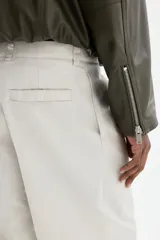 Pantalón sastrero de corte relajado en sarga color beige, con cierre y botón, bolsillos laterales y bolsillos traseros con botón oculto. Presenta piernas con pliegues.