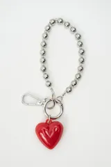 Llavero con correa de cuentas metálicas plateadas y dije de corazón rojo brillante. Incluye gancho mosquetón y argolla metálica.