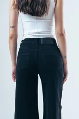 Jean de corte wide leg y tiro alto, color negro, con paneles laterales en el ruedo que aportan mayor amplitud y movimiento.