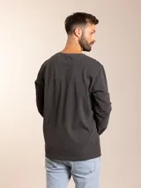 Remera de manga larga gris oscuro con cuello redondo y bolsillo en el pecho.
