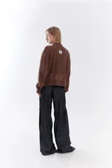Cardigan de tejido de punto color marrón, con cuello solapa, cierre frontal de cremallera y diseño de trenzas. Cuenta con puños y dobladillo en rib elástico y un pequeño bordado en el pecho.