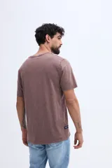 Remera de algodón con efecto lavado de estilo vintage, color marrón, con diseño de estampado tipográfico en el pecho.