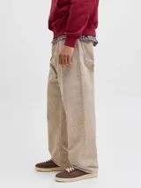 Pantalón de corte baggy y tiro alto, confeccionado en algodón con acabado lavado en tono beige. Presenta una silueta amplia y relajada, con cierre frontal de cremallera y bolsillos laterales y traseros.