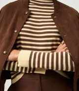 Sweater de punto de manga larga, con rayas horizontales en azul marino y blanco. Presenta cuello redondo ligeramente elevado y puños y ruedo en color blanco liso.