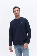 Remera tipo henley de manga larga en color azul marino, confeccionada en algodón con textura. Presenta una cartera con botones en el cuello y un pequeño logo bordado en el pecho.