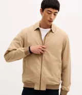 Campera bomber masculina de sarga color beige, con cuello inglés, cierre frontal de cremallera, bolsillos y elásticos en puños y cintura.