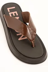 Sandalia tipo ojota Lemon de plataforma con base ancha negra y tira ancha de cuero marrón.