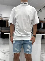 Remera oversize blanca de manga corta con cuello alto tipo polera, que presenta un estampado con texto en la parte del cuello.