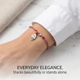 Pulsera de hilo trenzado en colores rojo y plateado, con dije colgante en forma de mano de Hamsa de acero inoxidable y cierre de mosquetón.