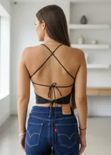 Top negro de diseño tipo halter con escote pronunciado y detalle central de argolla circular con pedrería brillante. Presenta un corte estilo mariposa que deja la espalda descubierta y se ajusta en la cintura.