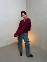Sweater de punto color bordó con diseño de volados en los hombros y mangas largas. Presenta una textura acanalada fina y corte holgado.