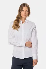 Camisa blanca de corte entallado, manga larga con puños abotonados y cuello clásico. Presenta cierre frontal con botones ocultos bajo una tapeta.