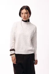 Sweater de tejido de punto con textura de pequeños relieves circulares, cuello redondo y mangas largas. Presenta un calce relajado con puños y ruedo acanalados.