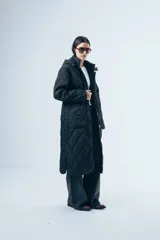 Campera acolchada de largo midi en color negro, con diseño de matelassé romboidal, cierre frontal con botones y capucha desmontable.