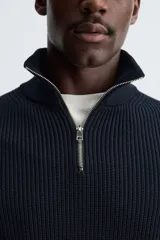 Jersey de punto perlado con cuello perkins y cierre frontal de cremallera. Presenta un corte regular fit, manga larga y acabados en rib en puños y bajo.