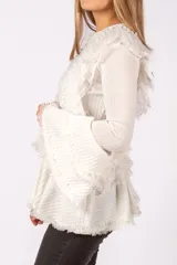 Sweater de punto acanalado color blanco, con diseño de volados en el frente y en las mangas acampanadas. Presenta detalles de encaje y terminaciones desflecadas.
