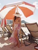 Falda playera larga estilo pareo, confeccionada en gasa estampada con diseño de algas marinas en tonos rosa, celeste, verde y blanco. Presenta cinturón anudado en la cintura y volantes en la abertura y el bajo.